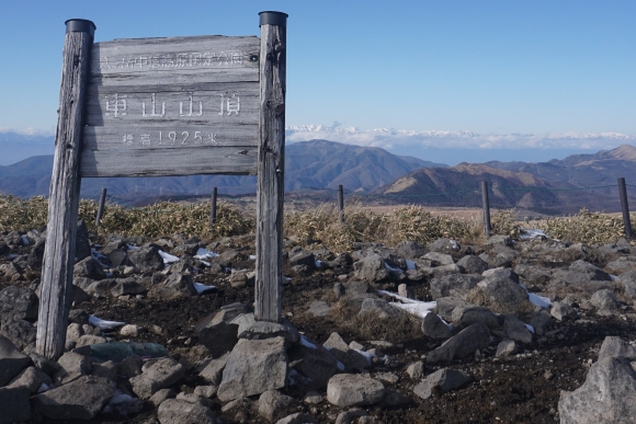 車山山頂からの景色、車山の山頂標の右側奥に北アルプスの白い稜線が見える