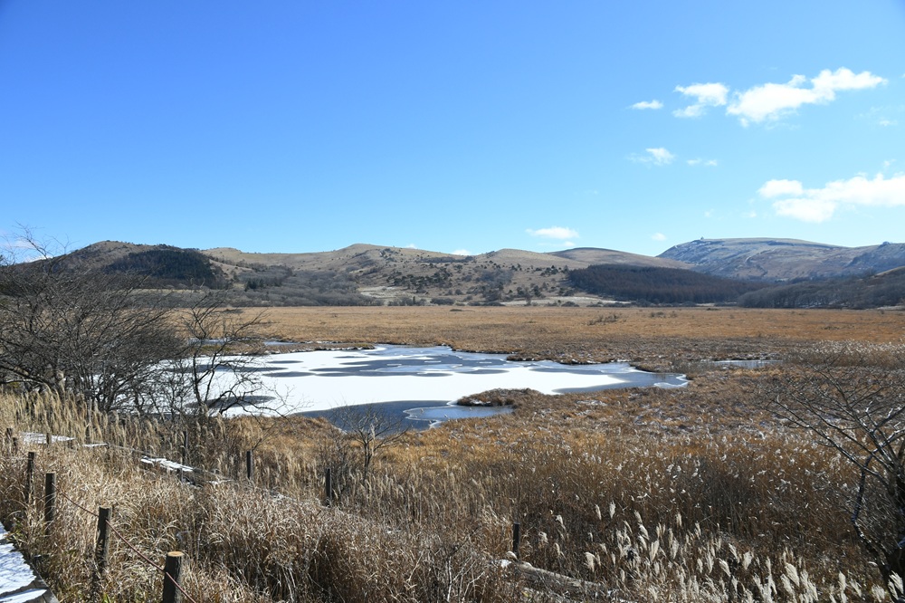 湿原の中の池が雪で一部白い