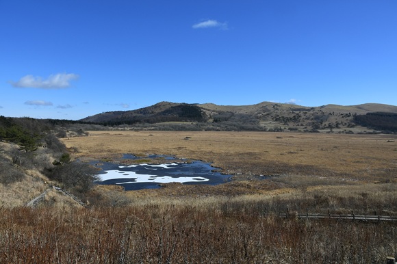 湿原と山々。手前の池が雪で白い